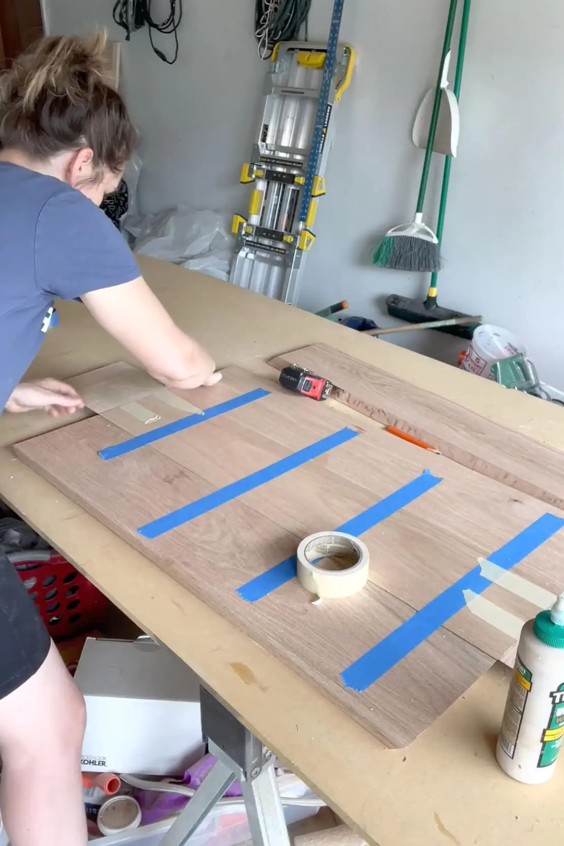 Taping oak boards together to align beveled edges while building a DIY fireplace mantel.